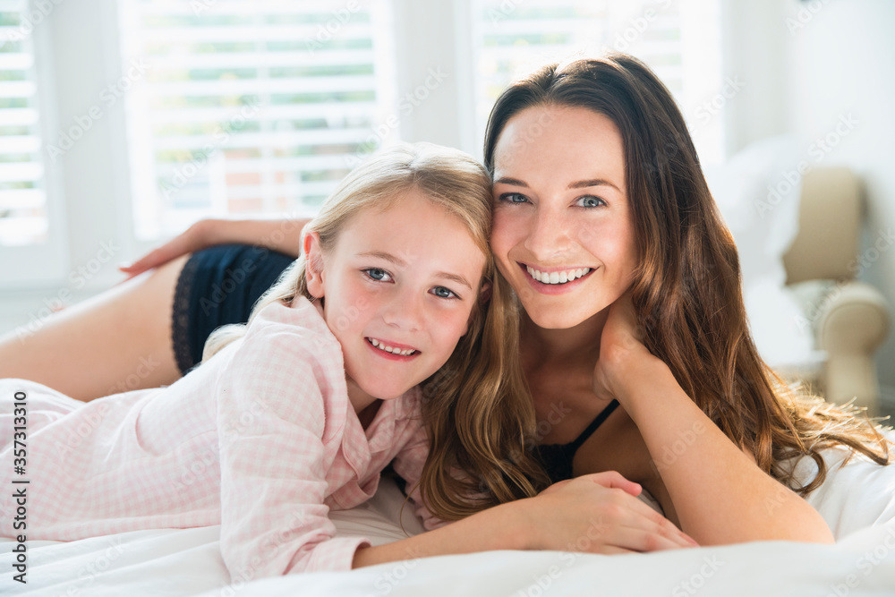 Portrait smiling mother and daughter laying on bed Portrait smiling mother and daughter laying on bed