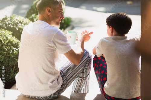 Fotografie Father with coffee talking to son on front stoop