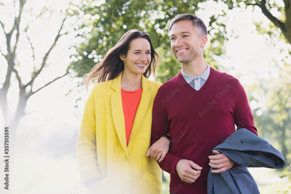 Obraz premium Couple walking arm in arm in park