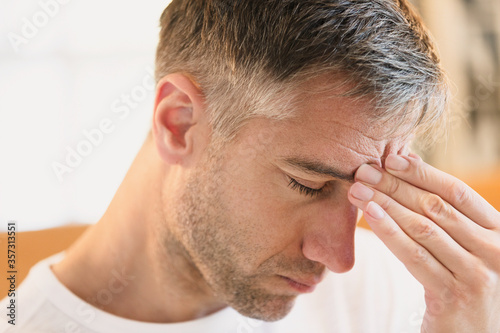 Close up of man with headache touching forehead