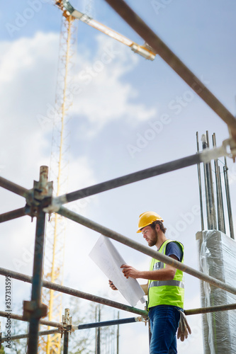 Engineer reviewing blueprints at high rise construction site