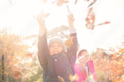 Enthusiastic boy playing in autumn leaves