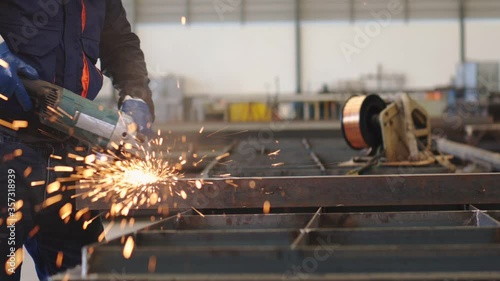 Electric wheel grinding on steel structure in factory
