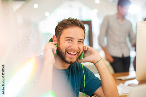 Behang Portrait enthusiastic creative businessman listening to headphones in office