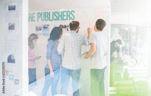 Publishers brainstorming at whiteboard in office
