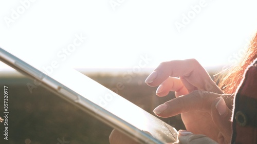 silhouette of female farmer with tablet studying wheat crop in field. close-up. agronomist girl works with tablet on wheat field in sun. business woman plans her income in field. grain harvest.