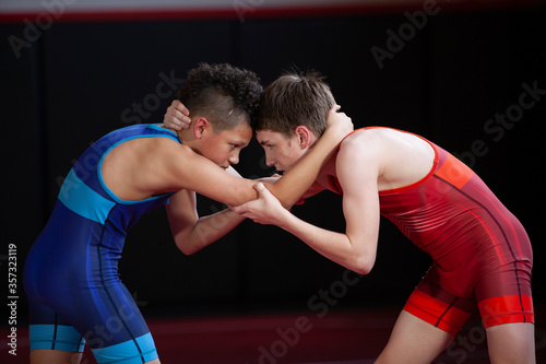 Canvas Print Wrestlers in red and blue singlets practicing on a red mat.