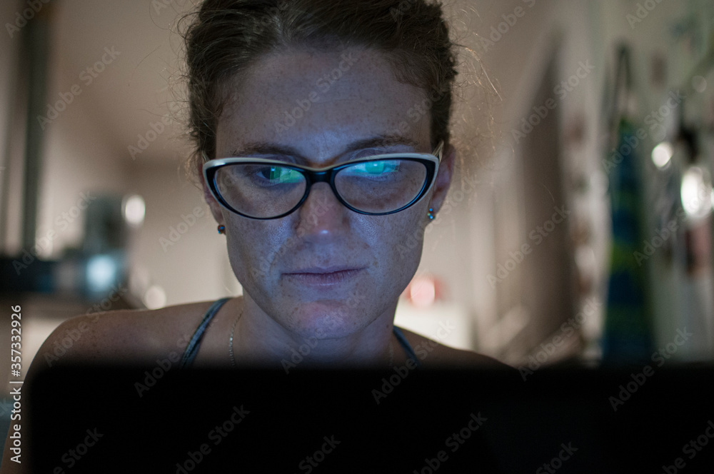 Young woman in glasses looking at a laptop screen, reflected on her glasses. Young woman in glasses looking at a laptop screen, reflected on her glasses.