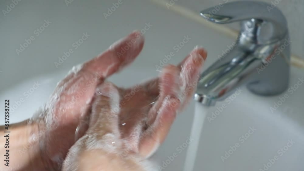 Hands of woman wash their hands in a sink with foam to wash the skin and water flows through the hands. Concept of health, cleaning and preventing germs and coronavirus from contacting hands Hands of woman wash their hands in a sink with foam to wash the skin and water flows through the hands. Concept of health, cleaning and preventing germs and coronavirus from contacting hands