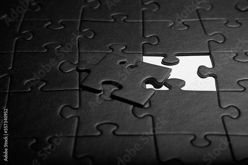 Puzzles in black. Monochrome cardboard shapes. Dark background.