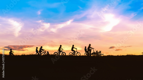 Silhouette of children friends on bicycles outdoors against sunset