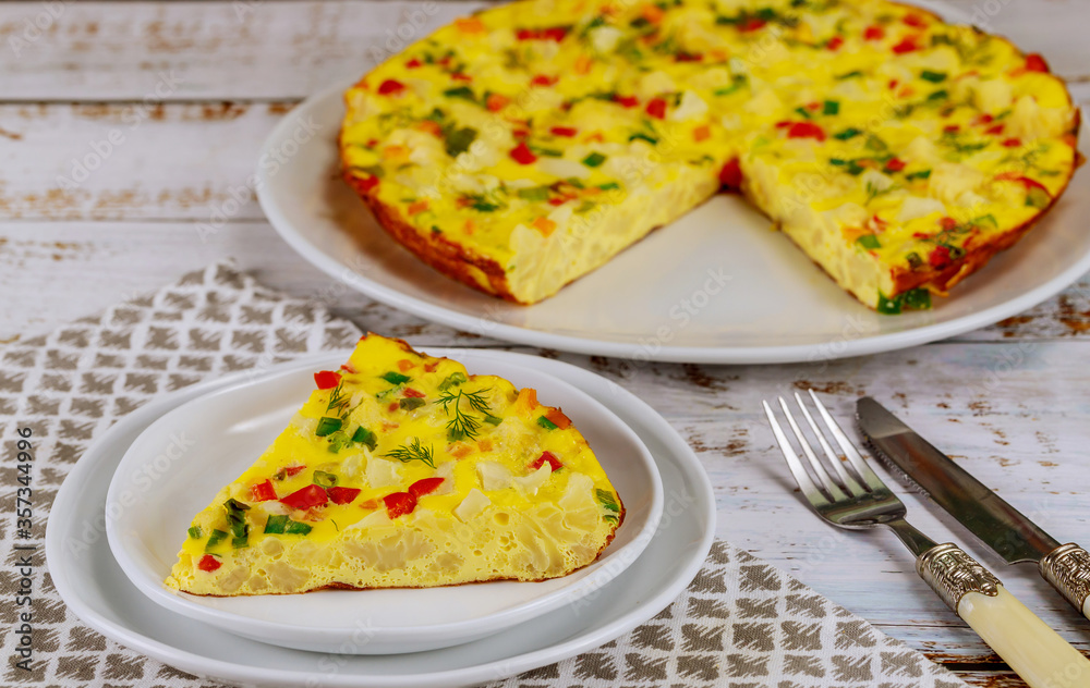 Homemade cauliflower omelette with fork and knife on white background.