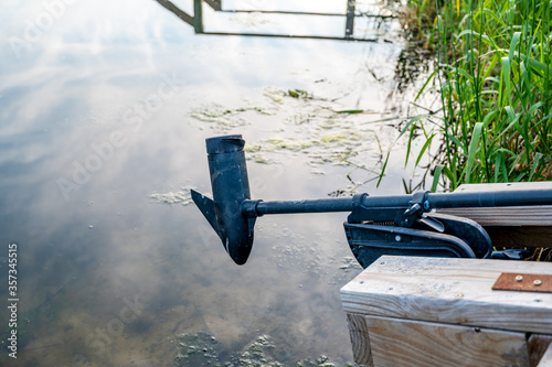 Boat trolling outboard motor extended over mossy water