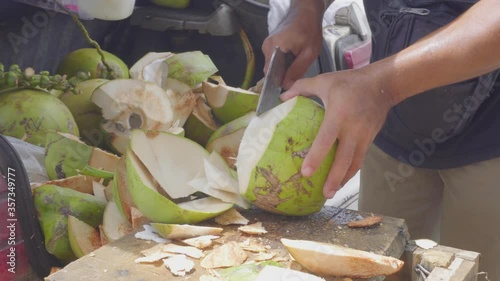 Green fresh coconut peeling and shelling with heavy chop knife for juice.