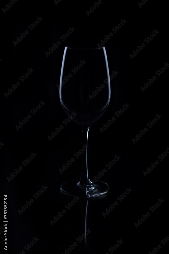 Wine glasses on light and shadow on a black background.