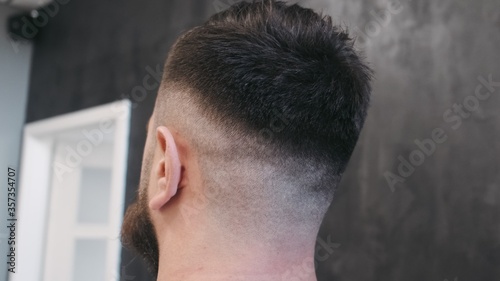 Young man posing after cutting and hairstyling in hair salon. Close up
