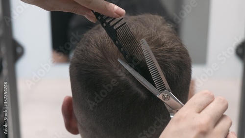 Professional female hairstylist combing and cutting man hair. Close up, slow motion