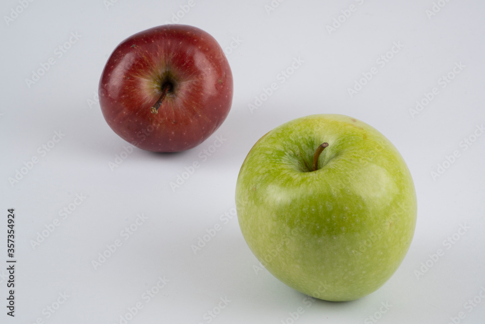 Green and red apples on a white background near each other