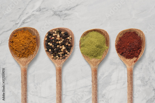 A pepper and spices in a wooden spoon background. Cooking set concept.