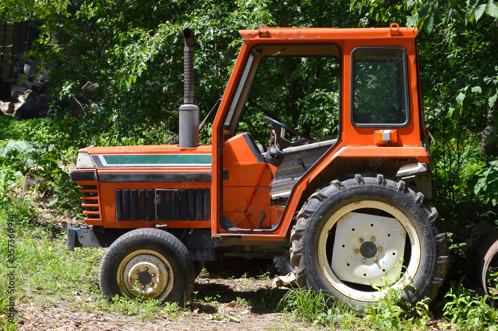 Old orange tractor with no doors, with a pipe. Russian countryside Old orange tractor with no doors, with a pipe. Russian countryside
