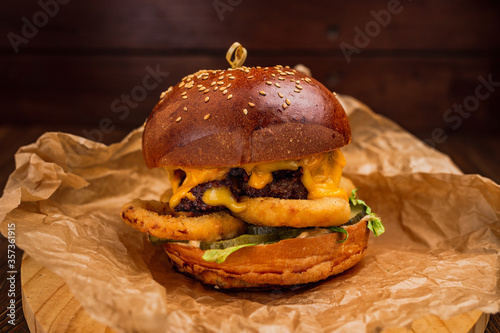A cheeseburger with onion rings on wooden board