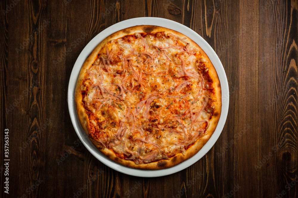 Ham and cheese pizza, wooden background, low key top view Ham and cheese pizza, wooden background, low key top view