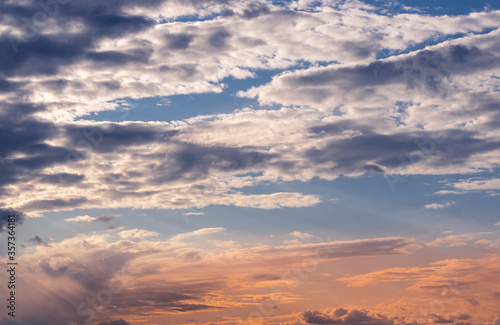 evening cloudy sky with mild golden sunset light , shinig through the colored orange clouds , nature landscape background photo