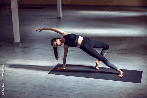 Young dedicated attractive slim yogi girl in Wild Thing yoga pose. Yoga studio interior.