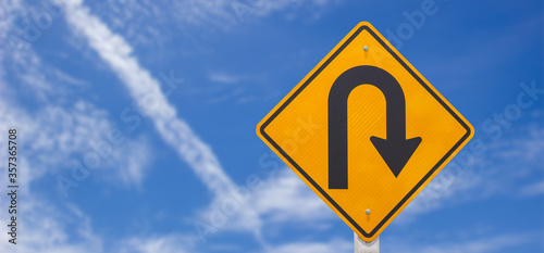 U turn road warning sign or symbol caution for change direction on white clouds and blue sky background