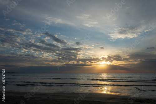 Tramonto sul mare con cielo nuvoloso e riflesso del sole sull'acqua.
