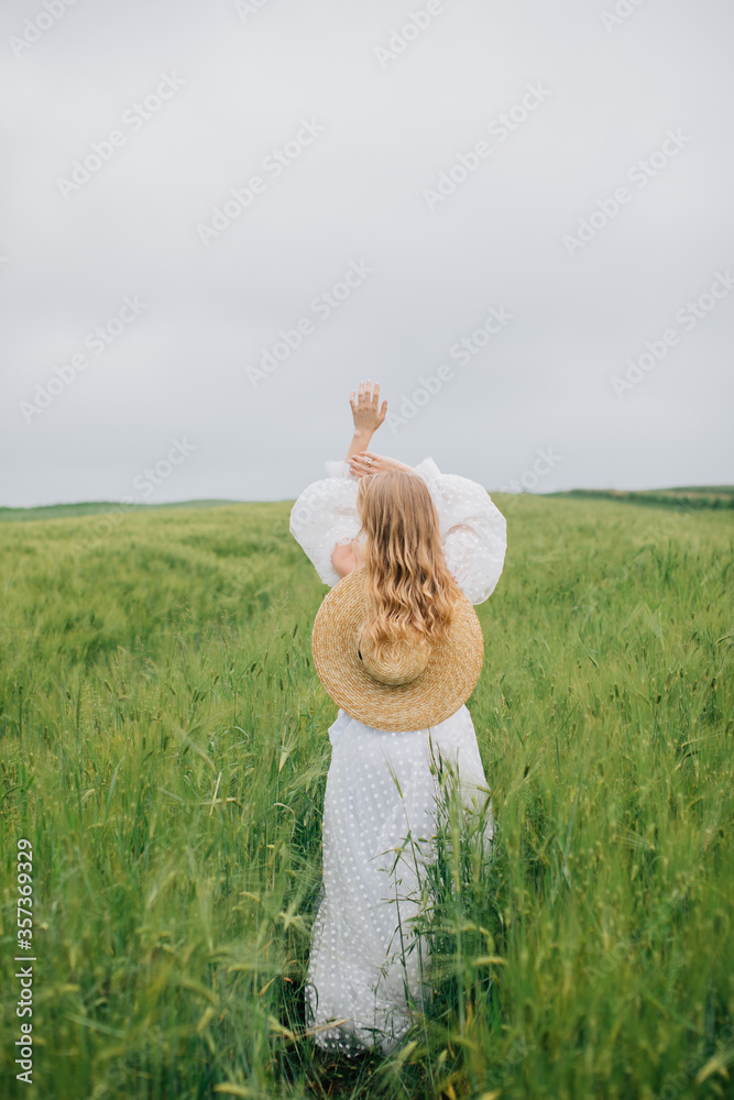 Girl in a field of rye in cloudy weather. He stands with his back