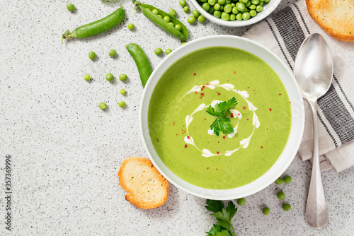 Bowl of green peas cream soup on gray stone background