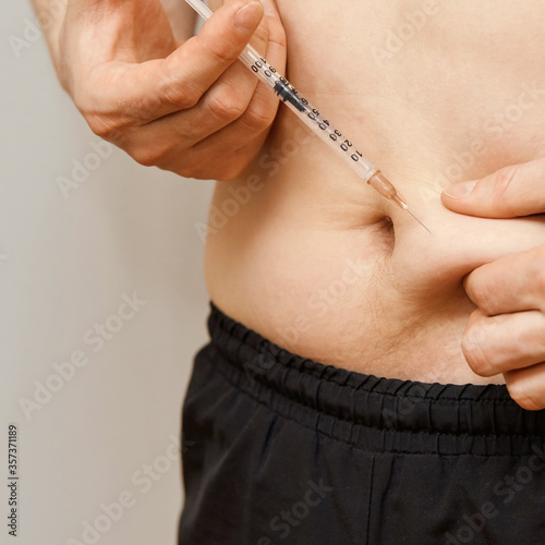 Obraz na płótnie Person injecting stomach medicine treatment. Diabet or hormone male injection. Men abdomen disease procedure. Hupodermia doctor hand shot. w salonie