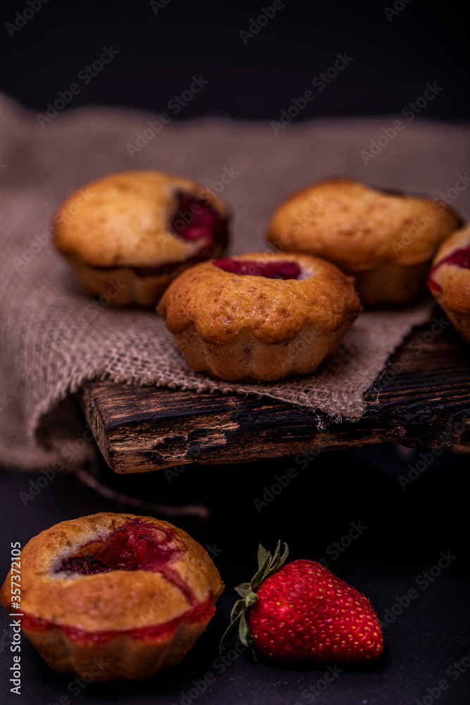 Strawberry muffin and coffee beans on a wooden board on a dark wood background. Chocolate muffins on dark background, selective focus.