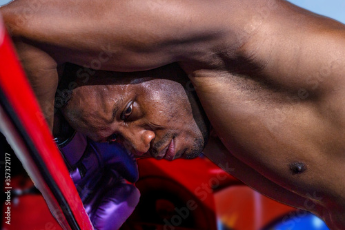 African American boxer takes a rest on his arms after a fight at a corner reflecting on his performance with hope eyes photo