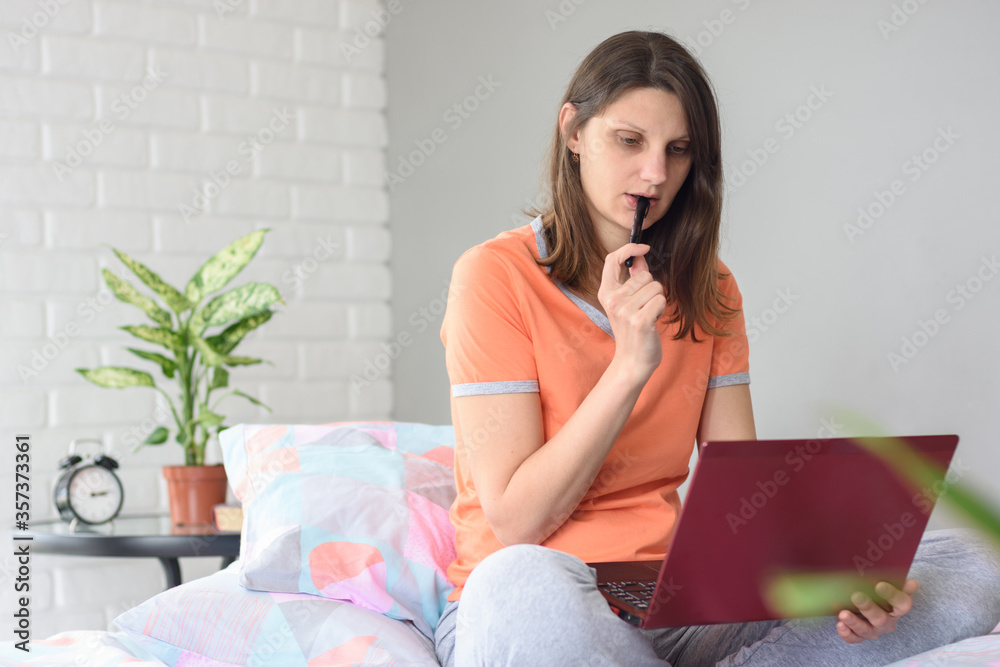 Girl watching a video tutorial and thoughtfully nibbles a marker Girl watching a video tutorial and thoughtfully nibbles a marker
