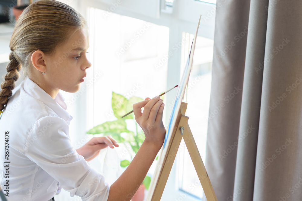 girl with great interest paints on easel
