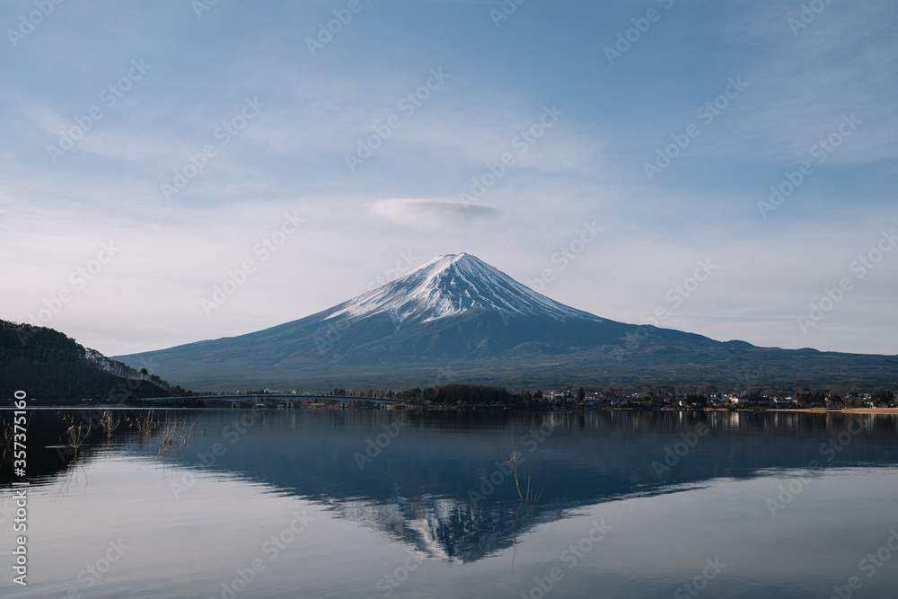 View of mountain Fuji with crown clouds and reflection on smooth water at Kawaguchiko lake.