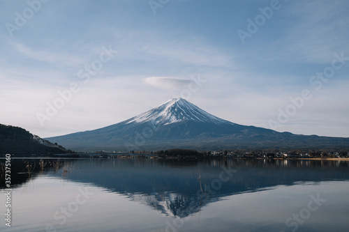View of mountain Fuji with crown clouds and reflection on smooth water at Kawaguchiko lake.