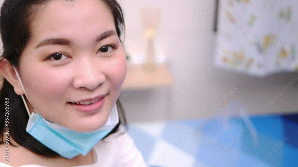 Beautiful Asian woman wearing a mask look camera and relaxing stay on the bed at home lifestyle and pleasure concept. Beautiful Asian woman wearing a mask look camera and relaxing stay on the bed at home lifestyle and pleasure concept.