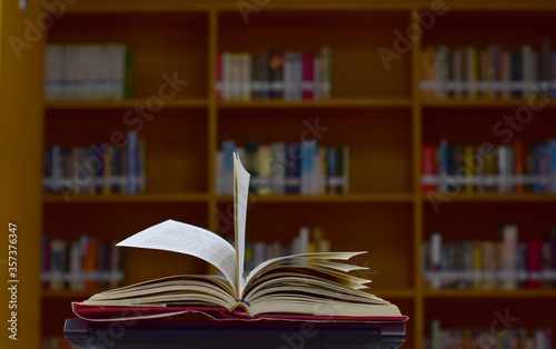 Open Book on wood table and blurred bookshelf in the library, education background, back to school concept.