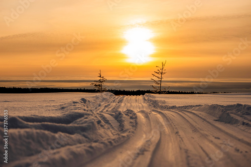 Scenic winter landscape of sundown over snowy road across the frozen river Yenisei in Siberia.