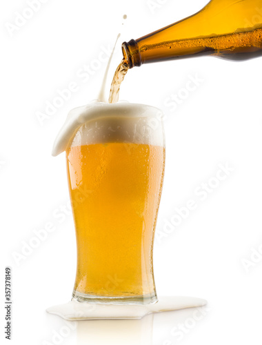 pouring blonde beer into glass with splashing foam, on white background