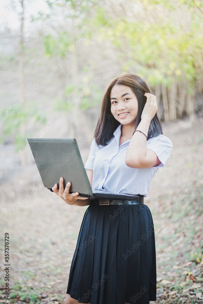 Asian young girl in school uniform are using laptop for education and communication at countryside of Thailand. Asian young girl in school uniform are using laptop for education and communication at countryside of Thailand.