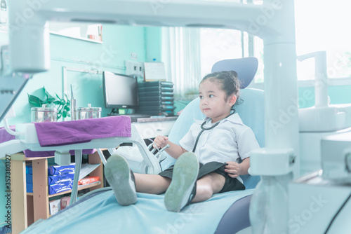 A Cute and lovely Asian baby girl in nurse uniform dress sitting on dental chair