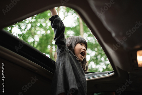 Foto little girl stood screaming with her hands up through the open roof of the car
