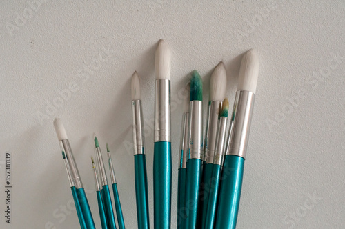Set of round pointed paint brushes on white stucco background