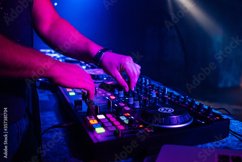 hands of a DJ playing music on a mixer at a concert