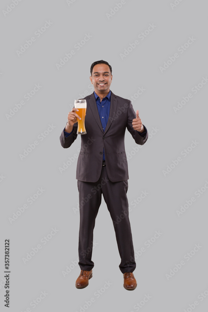 Businessman Holding Beer Glass Showing Thumb Up. Indian Business man Standing Full Length with Beer in Hand Businessman Holding Beer Glass Showing Thumb Up. Indian Business man Standing Full Length with Beer in Hand