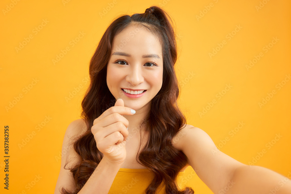 Portrait of cool cheerful girl holding smart phone in hand shooting selfie isolated on orange background enjoying weekend vacation Portrait of cool cheerful girl holding smart phone in hand shooting selfie isolated on orange background enjoying weekend vacation